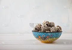 白木桌上的陶瓷杯里放着枣芝麻能量球。素食主义。复制spa。