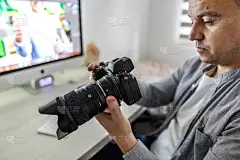 在营销和广告公司做会计工作。一名中年男子在检查拍摄现场的照片，为客户审批材料。Agency life