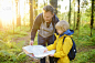 一个小学生和他成熟的父亲一起徒步旅行，探索大自然。小男孩和爸爸在森林里找地图。冒险，童子军和徒步旅行