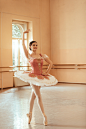 young-smiling-ballerina-practicing-dance-studio-looking-camera