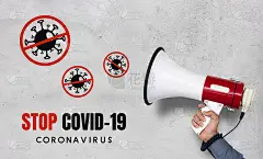 停止covid-19概念。白色砖墙背景上，手持扩音器的男子的手
