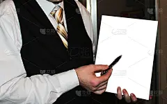 男人穿着白色衬衫，黑色背心和金色条纹领带拿着白纸