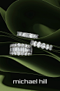 This may contain: two diamond rings sitting on top of a green leafy background with the words michael hill