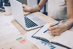 年轻的商业女性为新项目工作并在办公室的笔记本上记笔记。团队合作成功会议工作场所战略概念。为新项目工作