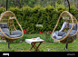 Rattan garden swing with cushion in the garden, seating area in the yard. Summer vacation concept Stock Photo - Alamy : Download this stock image: Rattan garden swing with cushion in the garden, seating area in the yard. Summer vacation concept. - 2JB3N6T