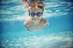 Little boy swimming underwater in pool