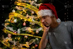 一个残疾人，一个戴着红色圣诞帽的男孩，一个患有营养不良症的人，坐在轮椅上，旁边是一棵装饰华丽、灯火辉
