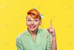 尤里卡。特写肖像快乐友好的年轻女子显示食指指向黄色的背景墙。海报女郎复古复古的50年代的发型。积极的