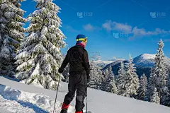 一位戴着护目镜的冒险家站在深雪中的群山中