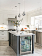 Transitional l-shaped gray floor kitchen photo in Toronto with a farmhouse sink, shaker cabinets, white cabinets, gray backsplash, glass tile backsplash, stainless steel appliances and an island