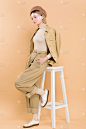 时尚的女人在贝雷帽站在口袋里的手在椅子附近孤立的米色 