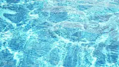 阳光泳池水背景。透明的美丽的蓝色水。桌面壁纸