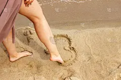 女人用她的脚心在海边的沙滩上画画