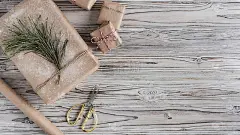 手工制作的礼物由手工纸、圣诞绳索和树在乡村木板的背景。DIY。