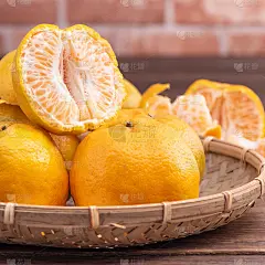 去皮的橘子放在竹筛篮上，深色木桌以红砖墙为背景，中国农历新年水果的设计理念，拉近了距离。