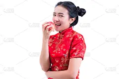 美丽的年轻亚洲妇女的肖像穿着中国传统旗袍或旗袍。吃红苹果，隔白底，健健康康，过年过节。