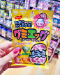 a hand holding up a packet of candy in a store aisle with other items on the shelves