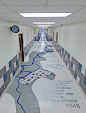 a long hallway with blue and white tiles on the floor, along with a clock