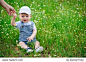 A small child sitting on the lawn with daisies