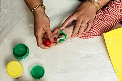 特殊教育的老师和学生穿着长袍，在桌子上用手画着生日花环和涂着丙烯颜料的黄色纸板。塑料工艺疗法。