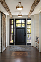 Example of a beach style dark wood floor and brown floor entryway design in Minneapolis with white walls and a black front door