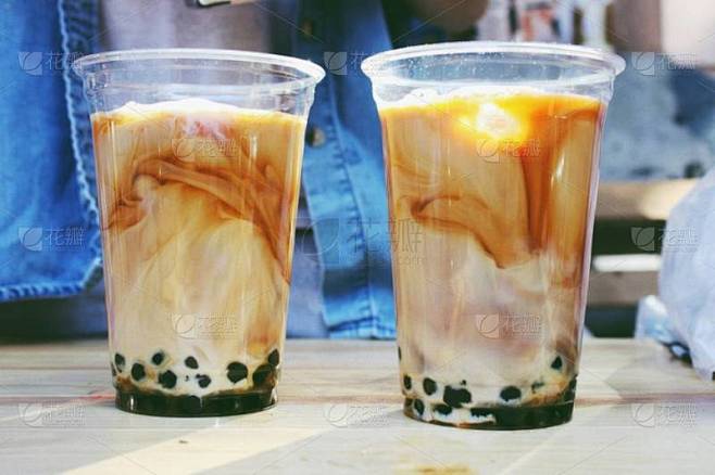 木桌上的两个棕泡茶塑料杯
