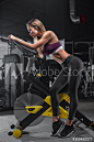 Beautiful young girl athlete doing exercises on a stationary bike in a modern gym.