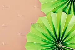 圆形纹理的绿色纸扇在棕色的背景
