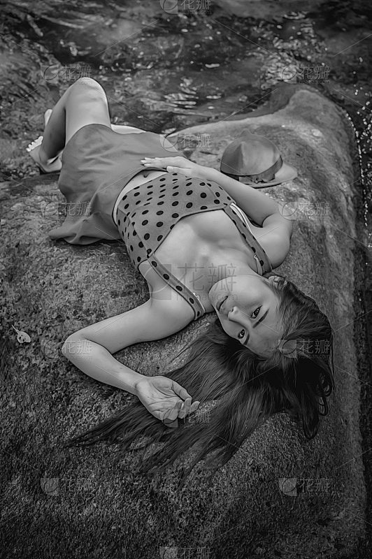 亚洲美丽年轻性感的女孩躺在一块岩石上
