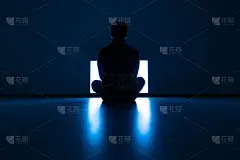 在黑暗的房间里，男性坐在电视机前的地板上