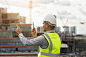 亚洲工程师帅哥或建筑师戴着白色安全帽在城市建筑工地使用无线电通讯。站在屋顶建筑施工的首都。