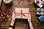 Crop hands holding wrapped present on table by Konstantin Kolosov on 500px