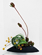 This may contain: an arrangement of flowers and plants in a black vase