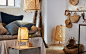 A white room with neutral textiles, rattan baskets, and a bamboo floor lamp, table lamp and pendant lamp.