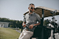 stylish golfer holding golf ball and looking away while leaning on golf cart