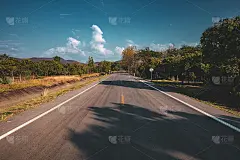 空旷的柏油路穿过绿色的田野和夏日蔚蓝的天空。