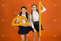 小学生可爱的女孩与大尺子。几何最喜欢的科目。教育和办学理念。学校学生学习几何。橙色背景的孩子校服。阻