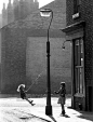 Shirley Baker “Girls swinging on a lamppost”, Manchester, 1965