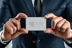 一个穿西装的男人手的特写显示一张名片。模型,布局。网络的概念，商务约会，重要的联系。在灰色背景下拍摄
