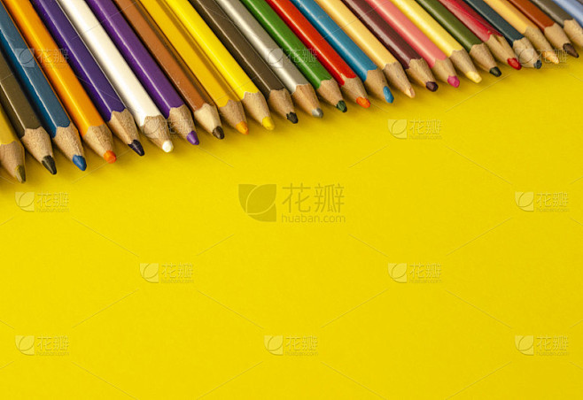 一组彩色铅笔，在黄色背景上，相互挨着，俯...