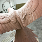 This may contain: a large pink bird statue sitting on top of a wooden table next to a mirror
