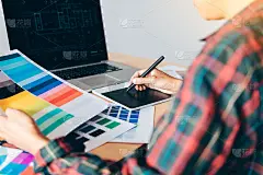 自由职业创意设计师使用数字图形板和绘图笔在现代家庭办公室办公桌上工作。