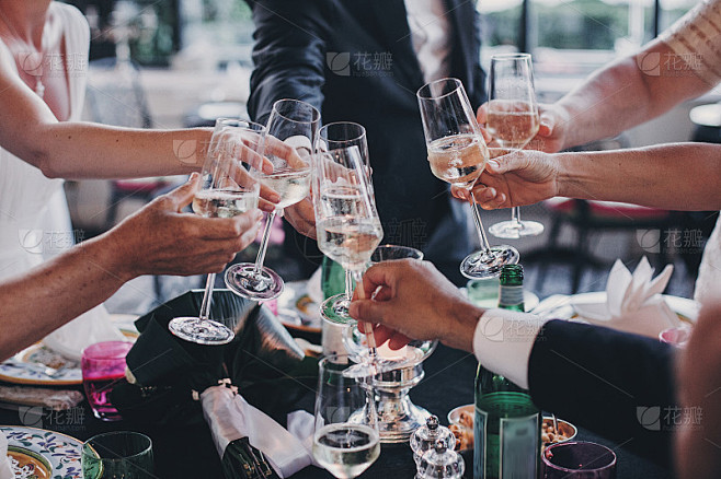 晚上在户外举行的婚礼招待会上，一群人手持香槟酒杯敬酒。家人和朋友们在美味的宴会上碰杯和欢呼