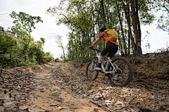 在山顶森林小径上骑自行车的女人