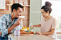 Free photo people, cooking and tasting concept. family couple has lunch at cozy kitchen: dark skinned bearded man eats delicious sweet croissant