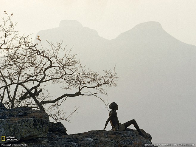 安哥拉，一名库瓦拉牧民坐在悬崖边上。远处...