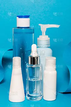 艺术色彩斑斓的几何蓝色风格和护肤化妆品。蓝色的折纸和白色和蓝色的化妆品:血清，面霜，润肤水。纸模型和
