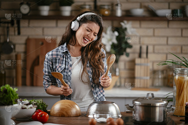 美丽的女人一边在家做饭一边听音乐。
