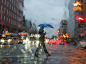 A woman walks with an umbrella across a rainy street in Washington, D.C.
