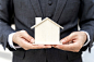 Close up asian business man holding model house - business finance concept